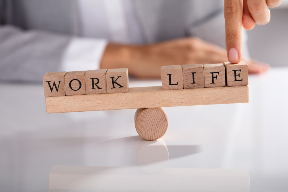 Businessperson's Finger Showing Imbalance Between Work And Life